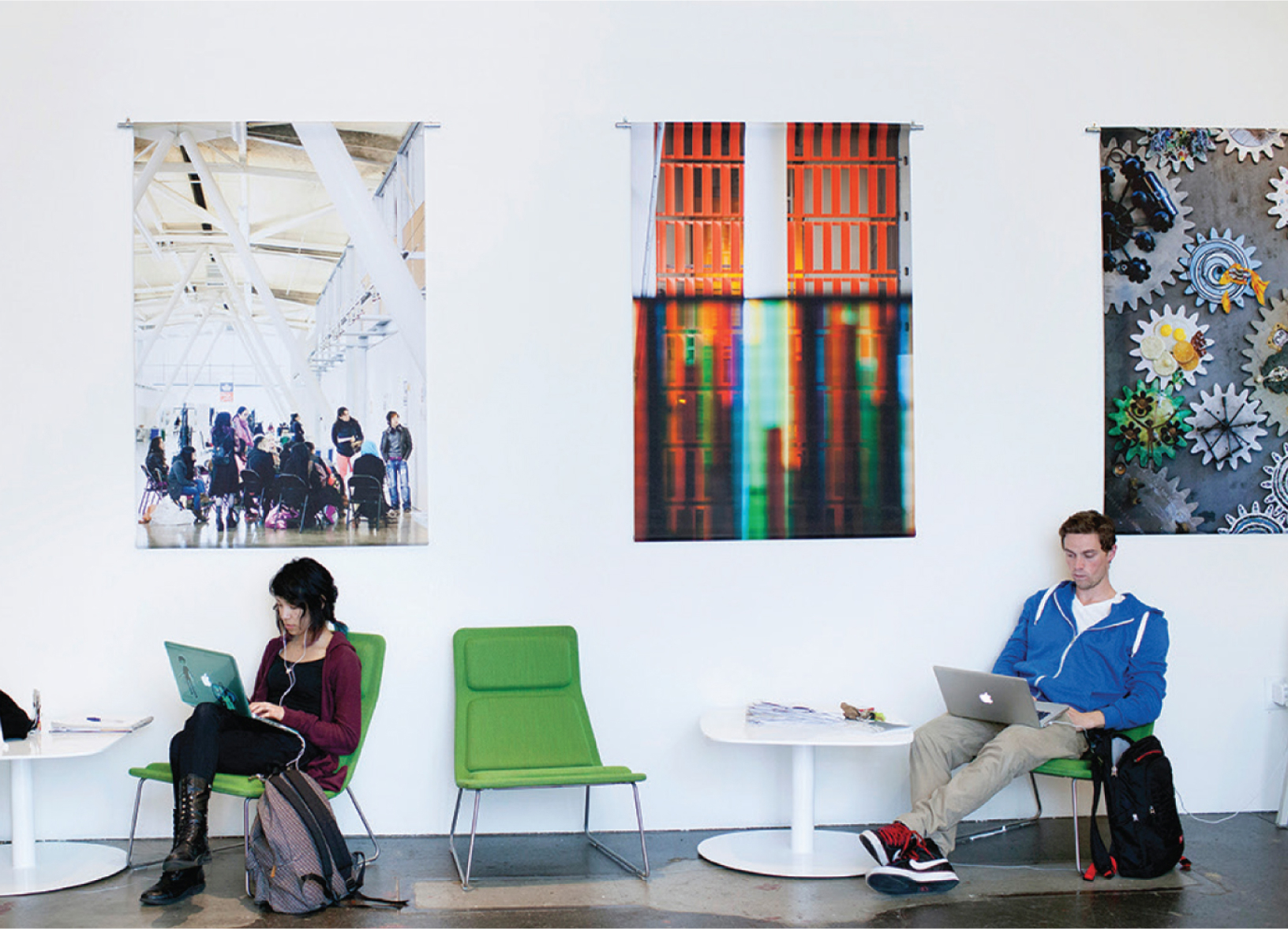 Students sitting in green chairs looking at laptops in an open room